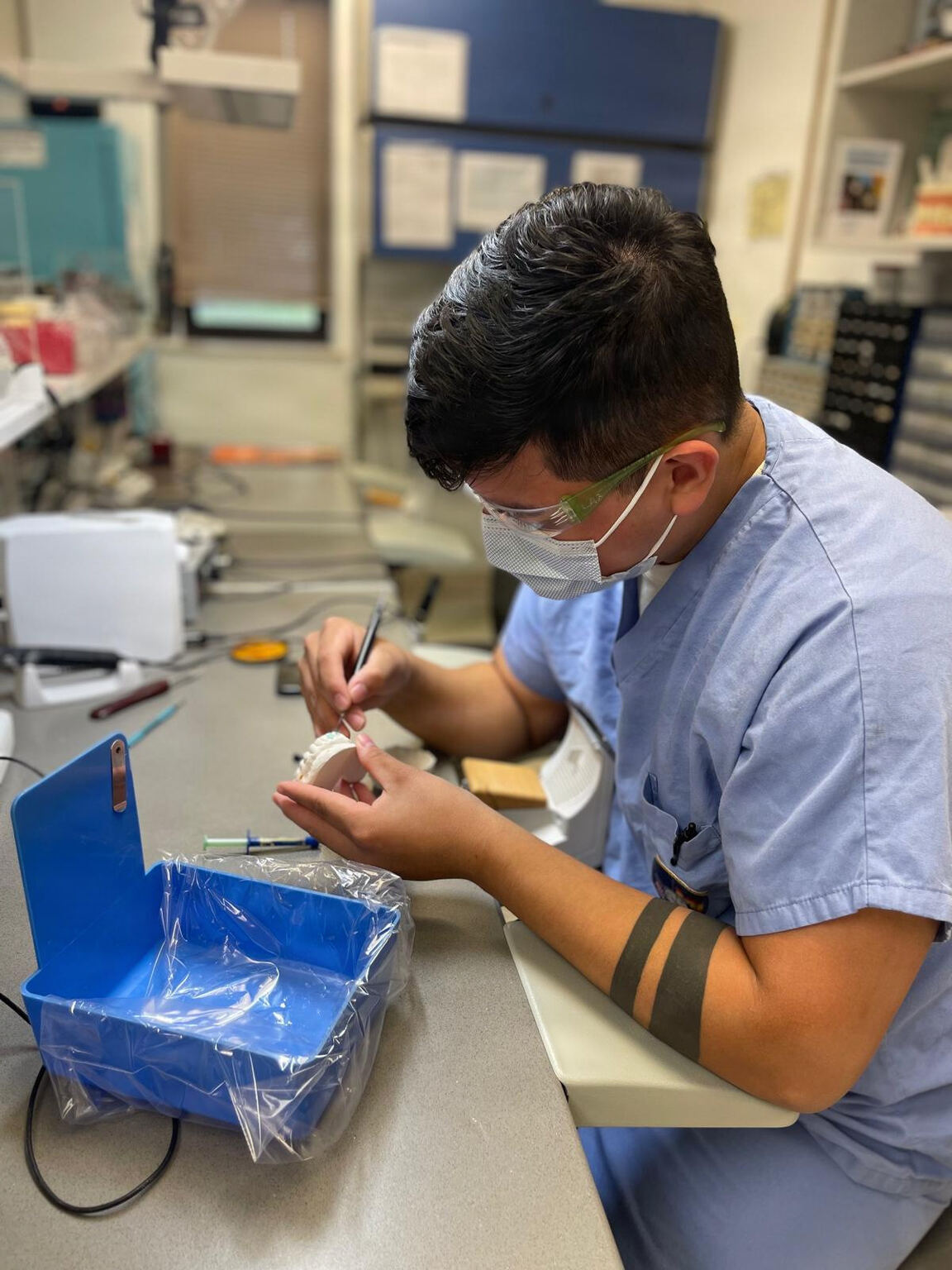 Dental lab technician hand-finishing a custom tooth restoration model with a fine tool