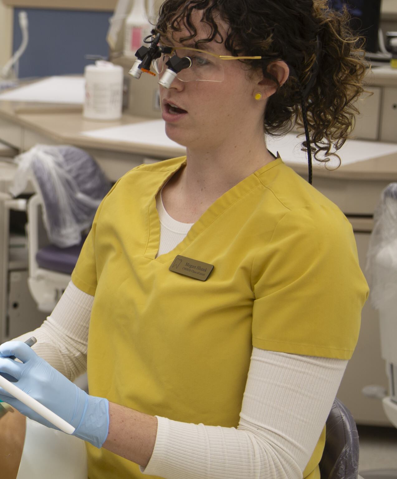 Dental clinician holding a pen-shaped intraoral camera wand near a model mouth during a demonstration